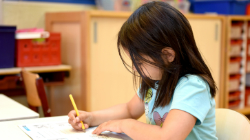 Meisje werkt aan opdracht in schrift op school.