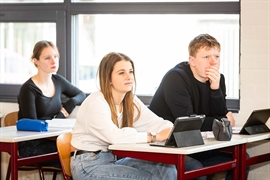 Leerlingen in het vo zitten met een laptop in de klas.