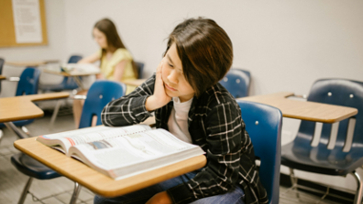 Leerling leest in een boek in de klas.