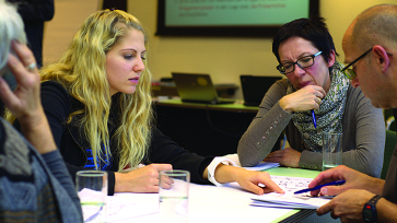 Onderwijsprofessionals overleggen aan tafel en bekijken een document
