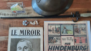 Historische krant ‘Le Miroir’ en poster ‘Nur Hindenburg!’ op een tafel met oude voorwerpen