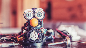 Robot van elektronische onderdelen met grote ogen op een tafel.