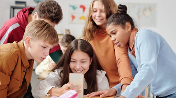 Leerlingen kijken samen op de mobiele telefoon van een leerling