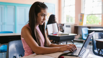 Een leerling werkt in de klas op haar laptop.