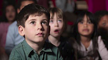 Leerlingen kijken aandachtig naar een groot scherm.