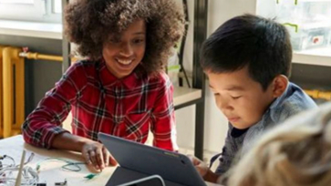 Leerling en lerares kijken samen op de tablet van de leerling.