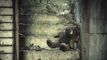 Versleten teddybeer op een verlaten trap in vervallen gebouw