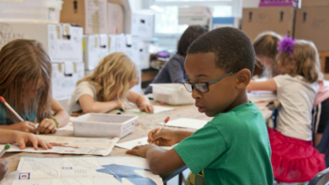 Leerling met bril op maakt tekening in de klas.