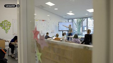 Klaslokaal gezien door een raam terwijl een leraar lesgeeft aan leerlingen