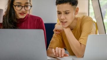 Twee leerlingen kijken aandachtig naar een laptop.