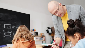 Leraar geeft uitleg aan een leerling in de klas.