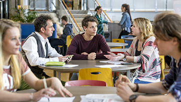 Onderwijsprofessionals zitten aan overlegtafels.