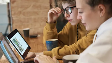 Leerling en leraar kijken samen op een laptop